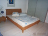 [Obrázek: Dřevěná postel Casandra s opletením z přírodního ratanu]